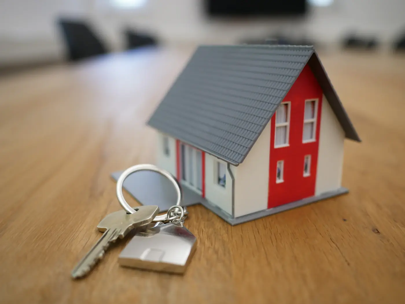 Toy house model with keys resting on investment paperwork