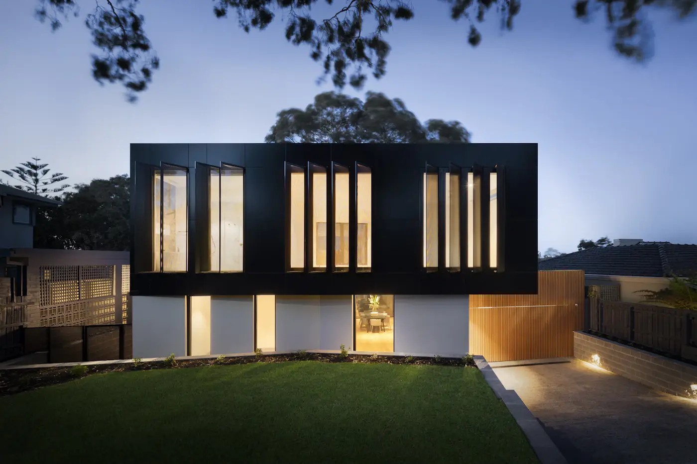 Modern house exterior at dusk with lit windows