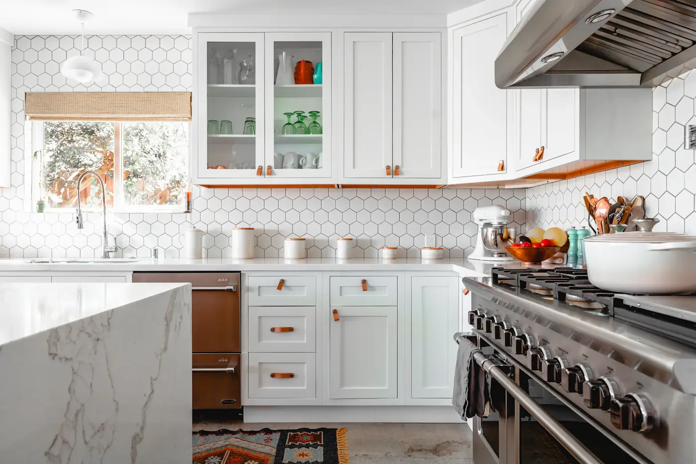 Bright renovated kitchen with white cabinets, hexagonal tile, and marble island