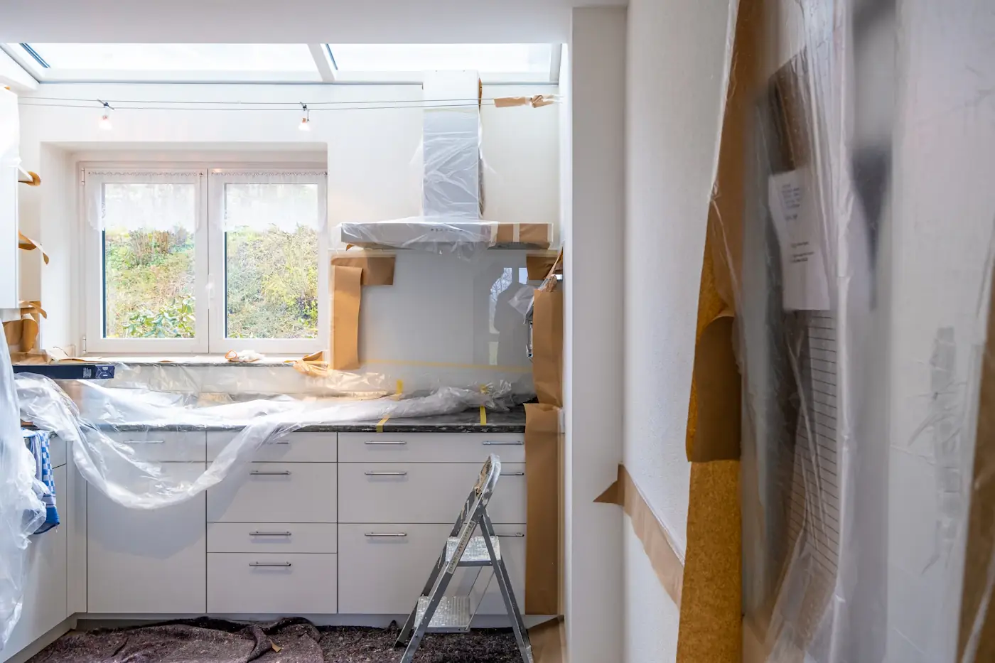 Kitchen mid-renovation with cabinets covered in protective plastic