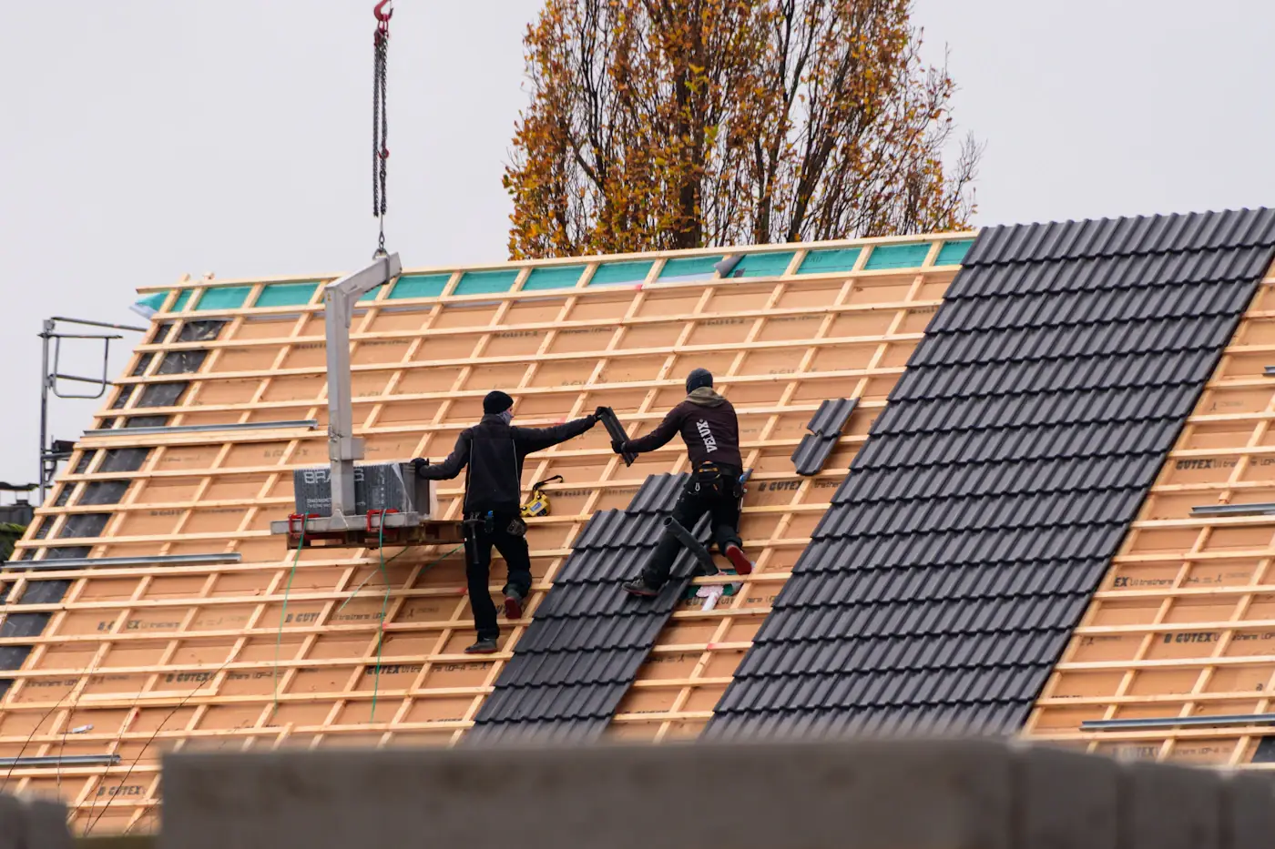Construction workers installing roof tiles on a building